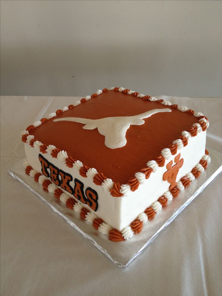 a cake that is sitting on top of a table with white and orange frosting