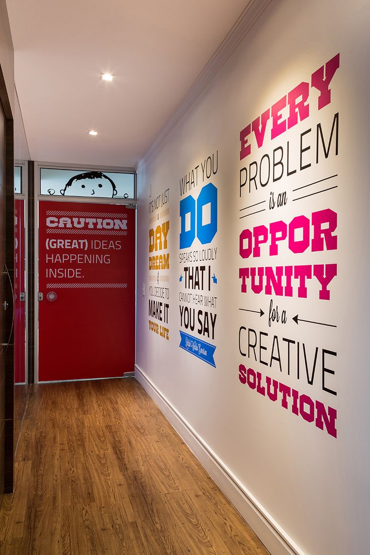 an office hallway with posters on the wall and wood flooring in front of it