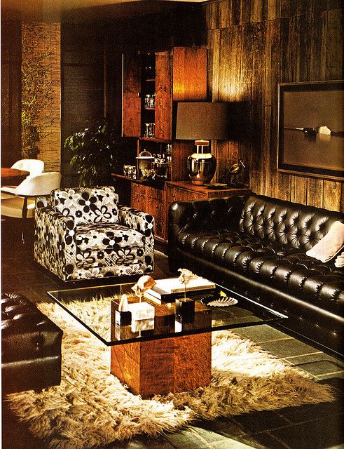 a living room filled with black leather furniture and lots of wooden paneling on the walls