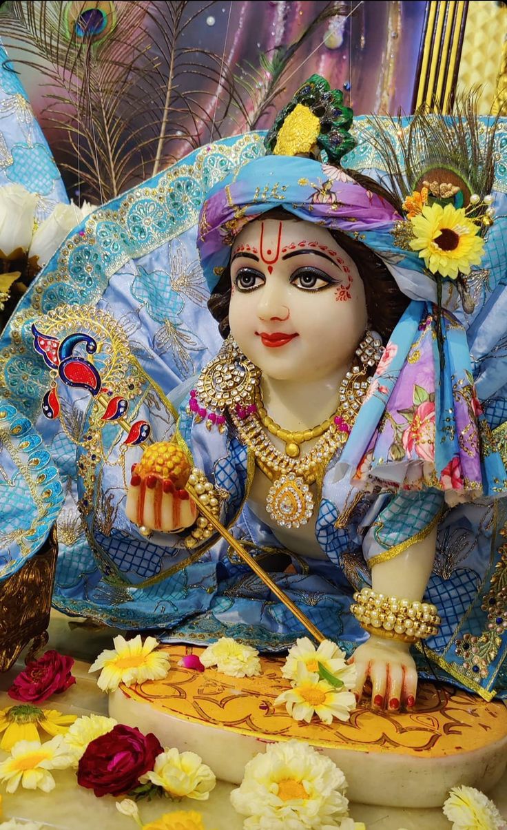 a statue of the hindu god ganesh is shown in front of flowers and feathers