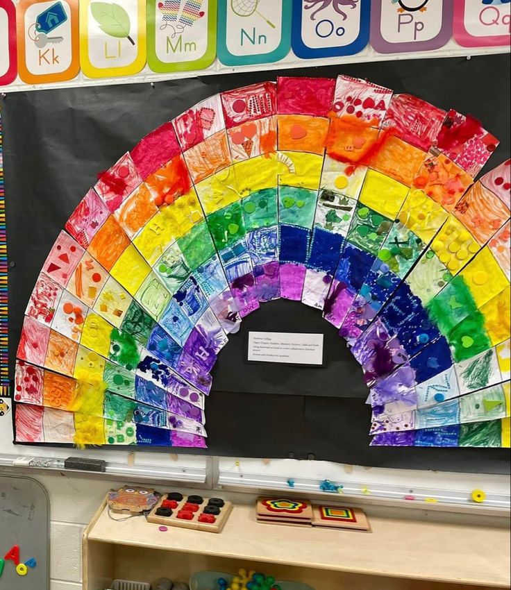 a rainbow made out of different colored papers on a table in front of a blackboard