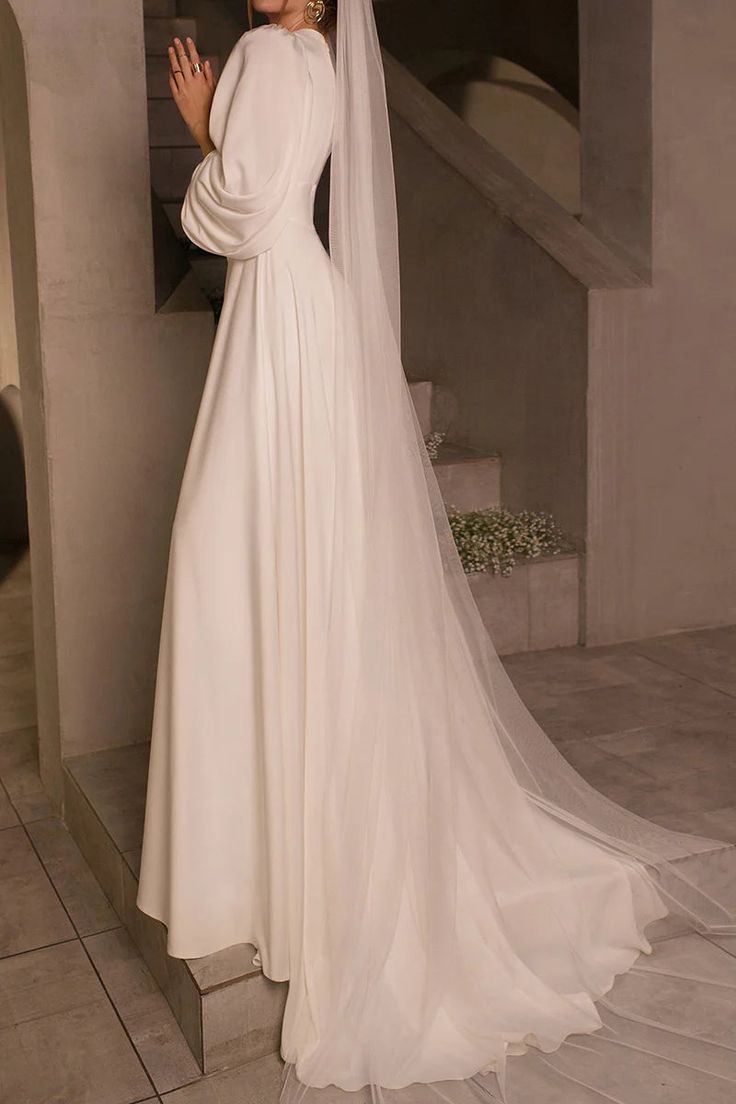 a woman in a white wedding dress standing next to a stair case and wearing a veil