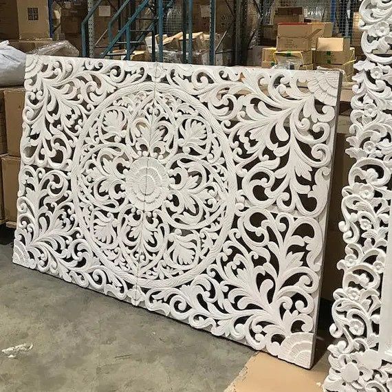 two white carved wood panels sitting next to each other on top of pallets in a warehouse