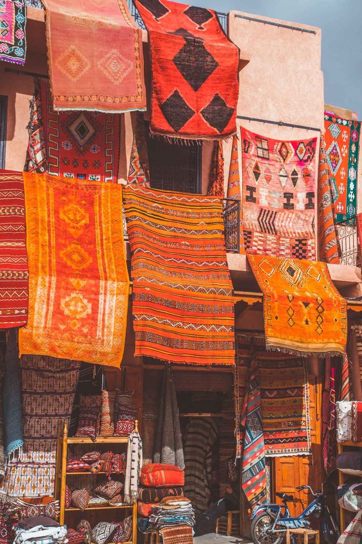 an outdoor market with many colorful rugs on display