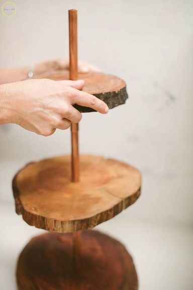 a person holding a wooden stick on top of a tree slice stand with another hand reaching for it