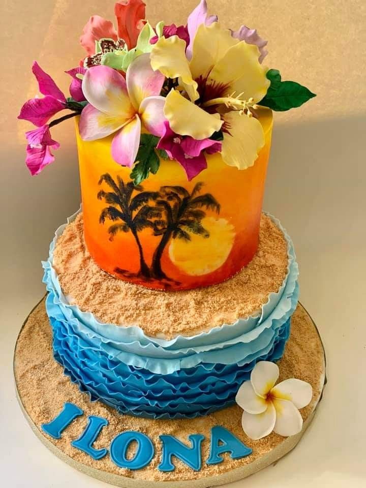 a three tiered cake decorated with flowers and palm trees