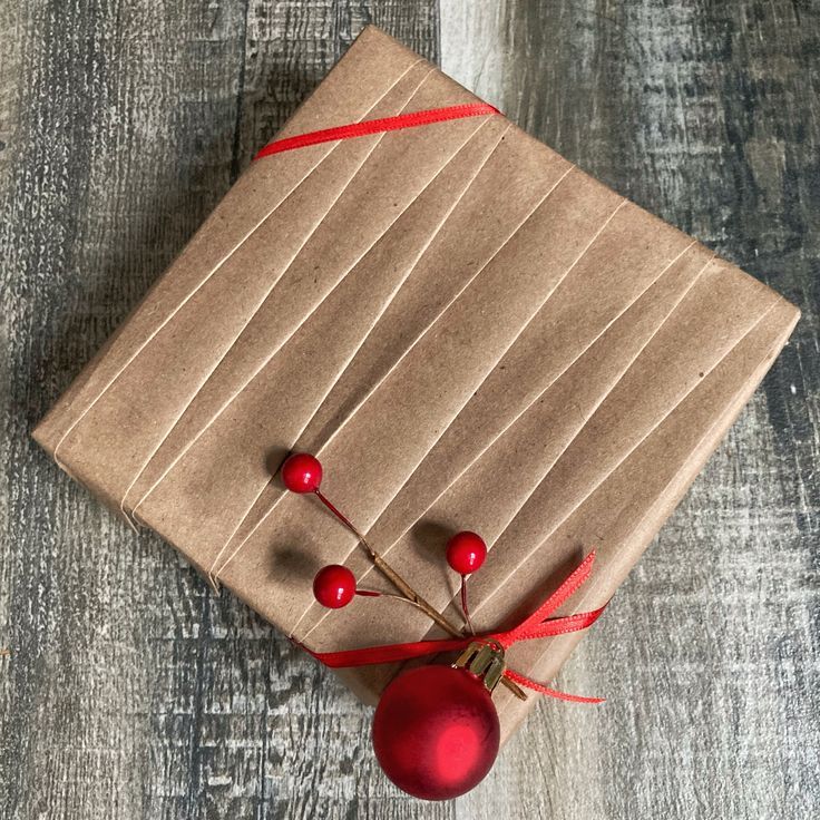 a present wrapped in brown paper and tied with red ribbon on top of a wooden table