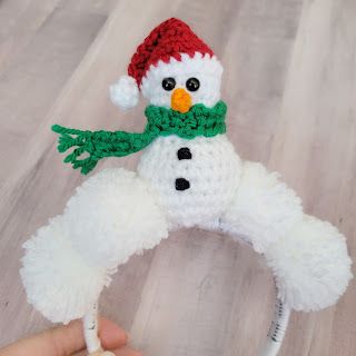 a crocheted snowman hat and scarf is being held by someone's hand