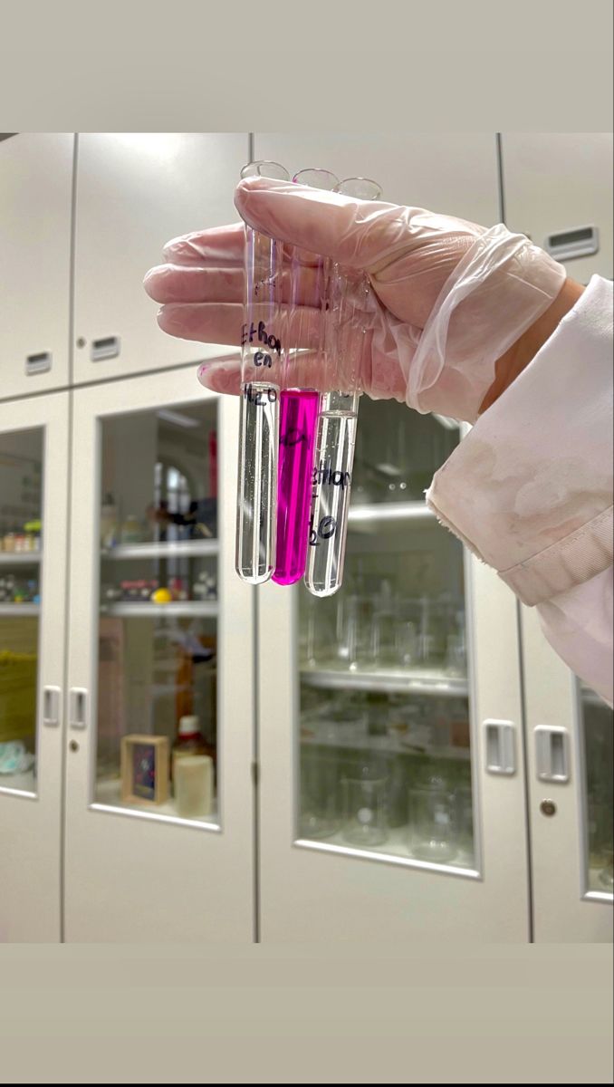 a laboratory worker holding two test tubes filled with liquid