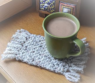 a cup of hot chocolate sitting on top of a wooden table next to a book