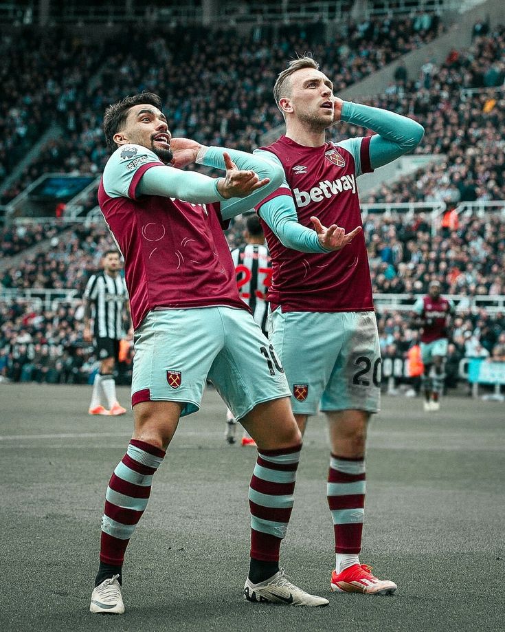 two soccer players standing next to each other in front of a crowd at a stadium