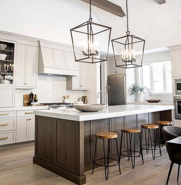 a kitchen island with stools in front of it and lights hanging from the ceiling