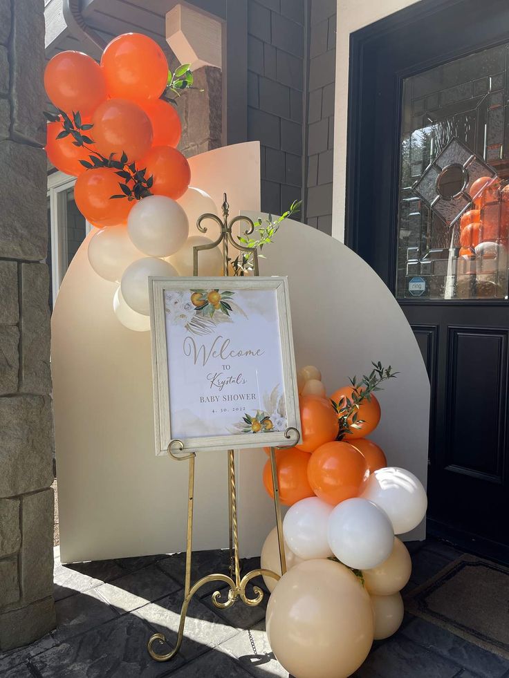 an orange and white wedding sign surrounded by balloons