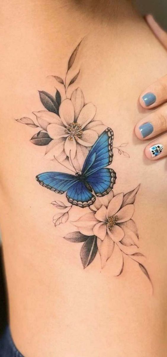 a woman's stomach with a blue butterfly and flowers on the side, in front of her