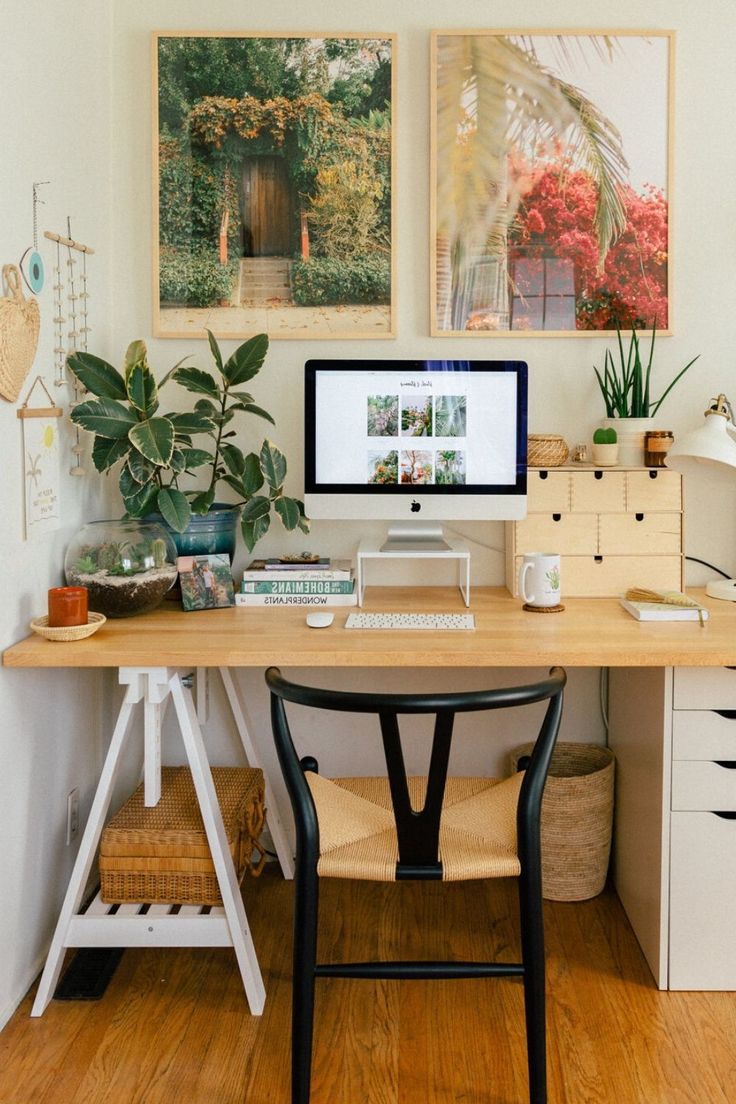 a desk with a computer on top of it next to a plant and other items