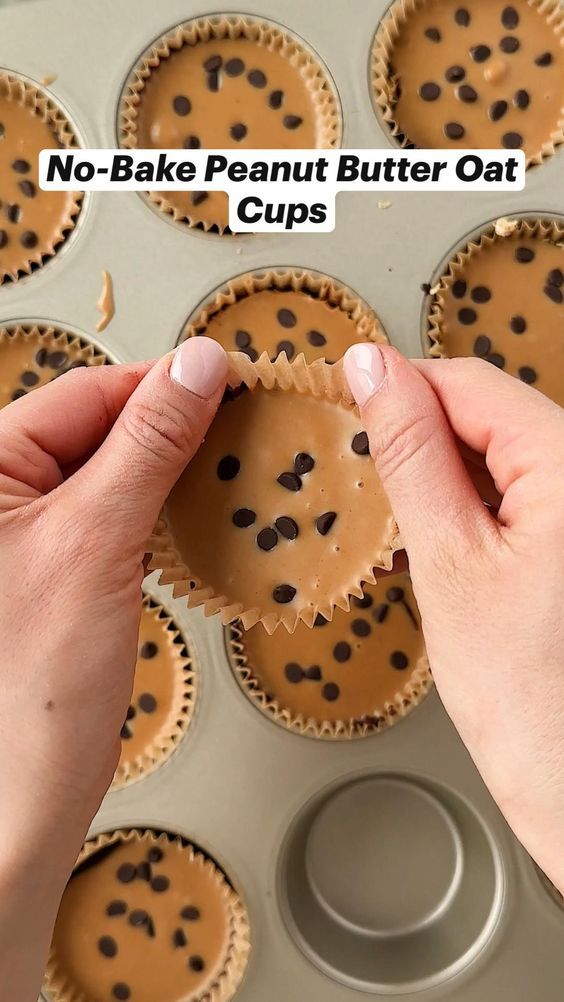 a person holding a peanut butter oat cup in front of a muffin tin