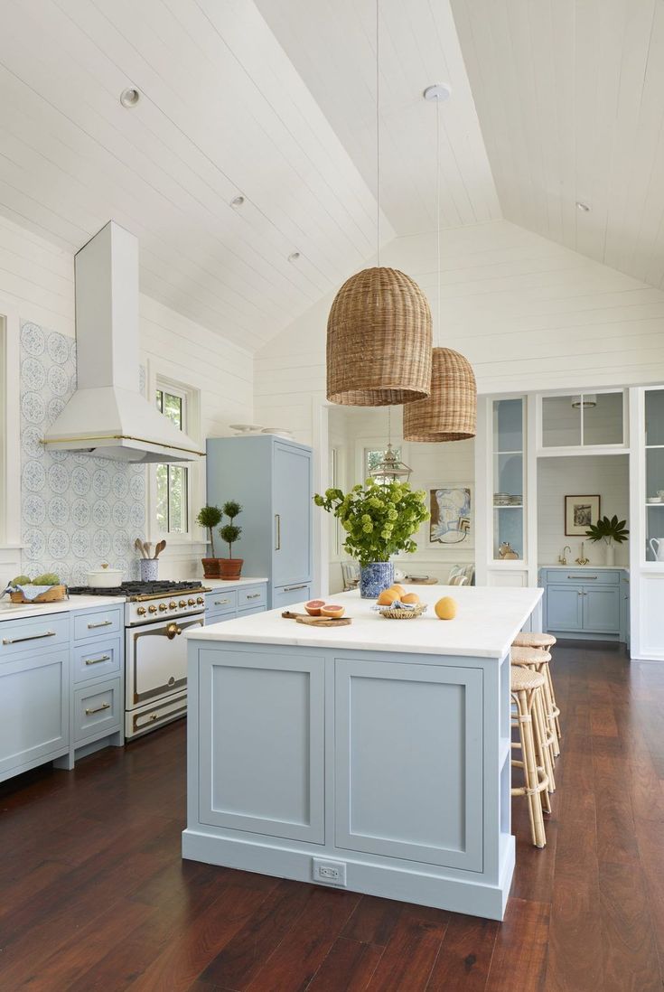 a large kitchen with blue cabinets and white counter tops, an island in the middle