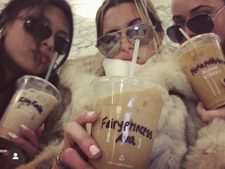 three women wearing sunglasses and drinking coffee together in front of a wall with the words fairy princess on it