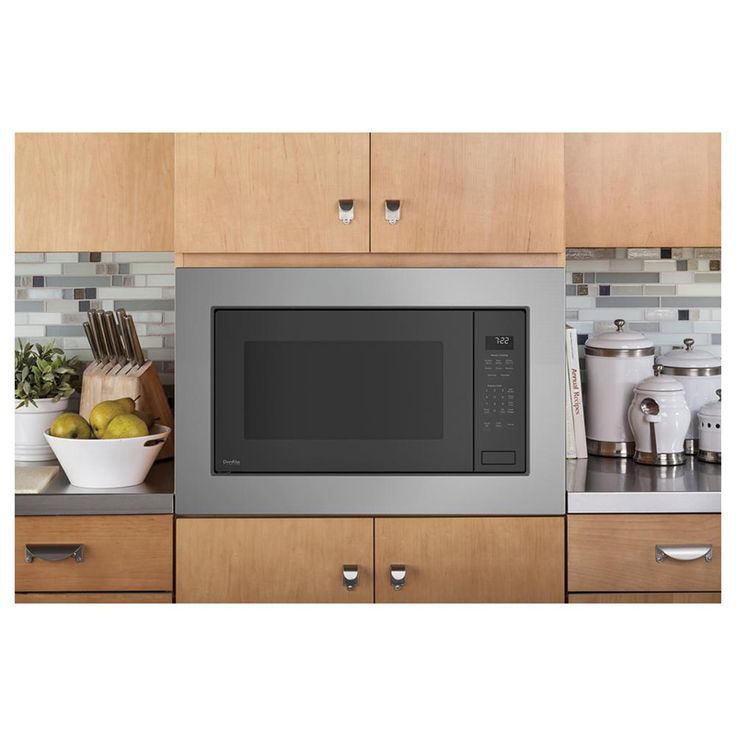 a stainless steel microwave oven sitting on top of a kitchen counter next to wooden cabinets