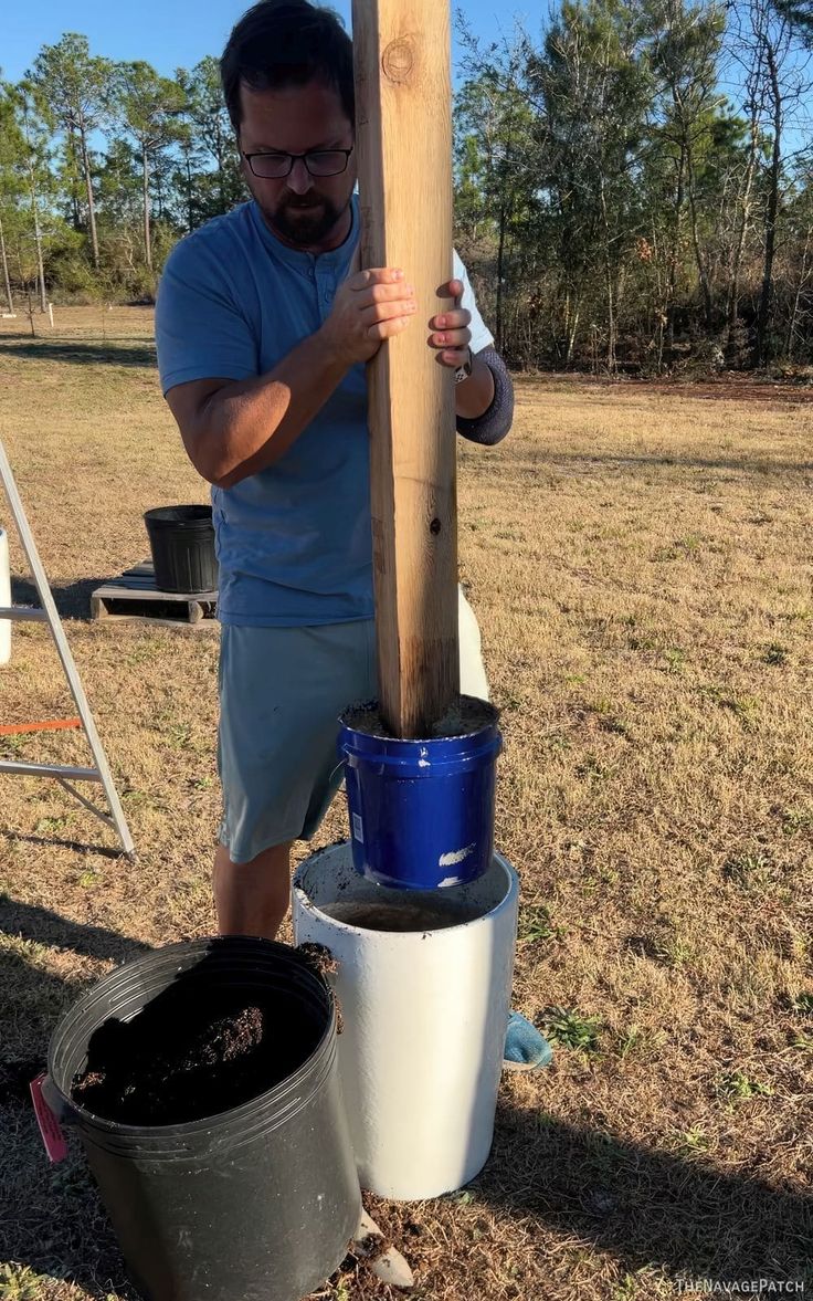 a man holding a wooden pole next to two buckets