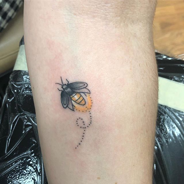 a tattoo on the leg of a person with a bee on it's side