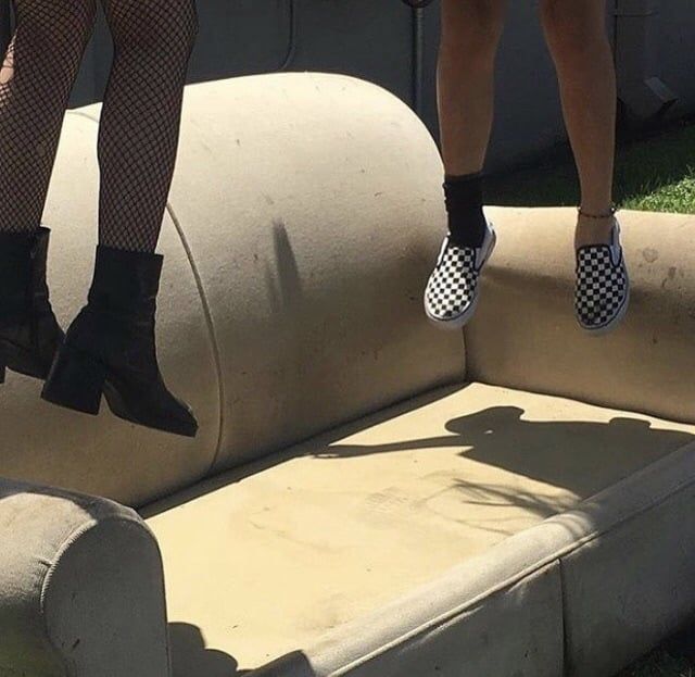 two people standing on top of a couch in the grass