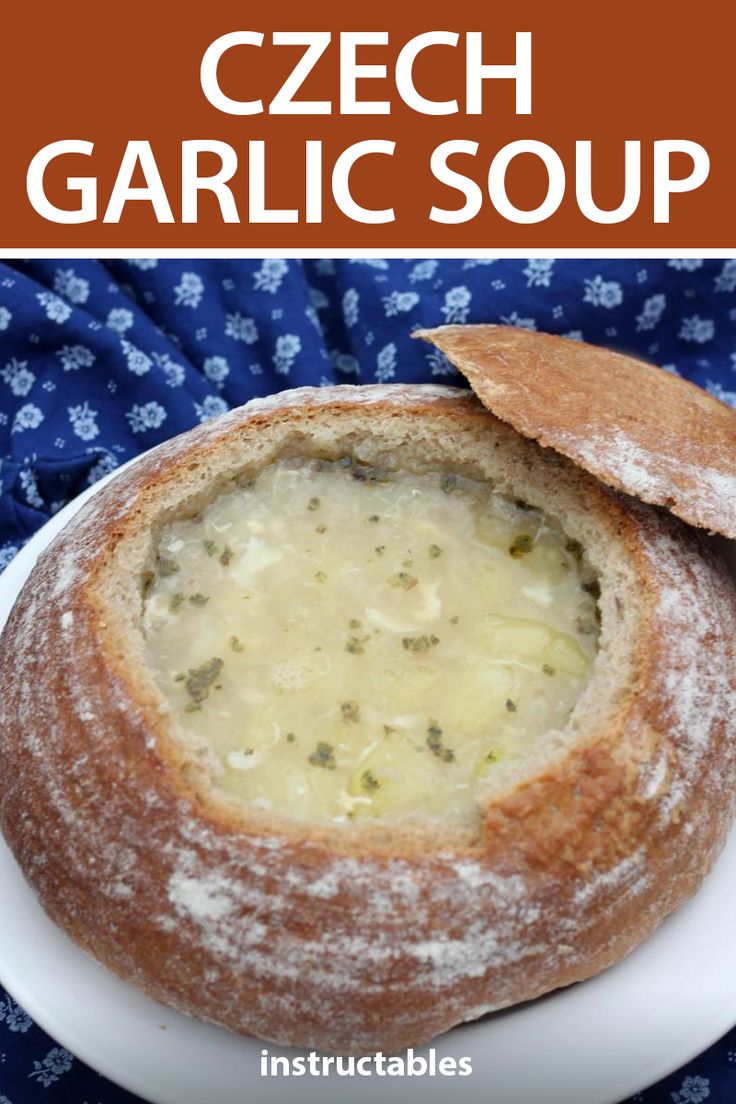 a close up of a bowl of soup on a plate with bread in the background