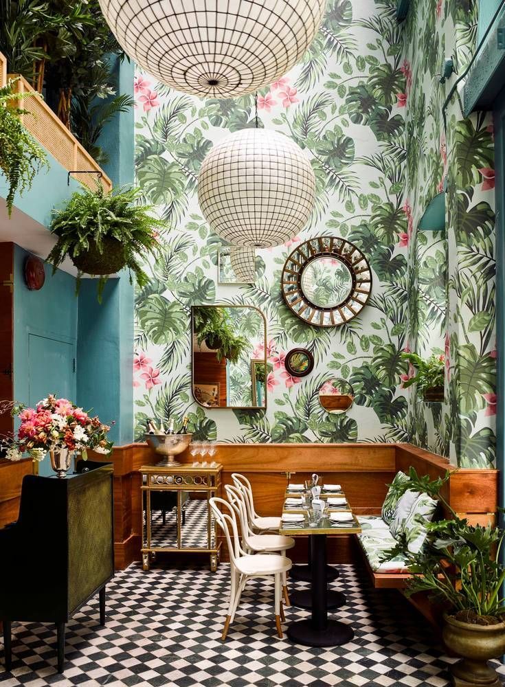 the interior of a restaurant decorated with tropical wallpaper and potted plants on the walls