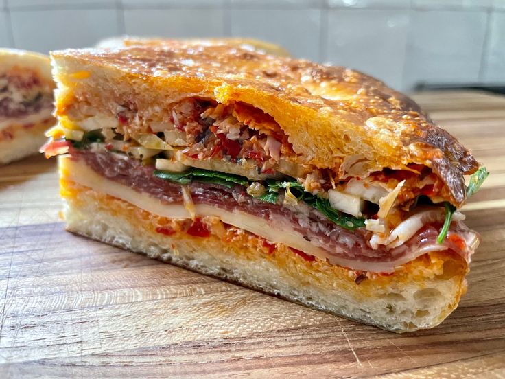 a cut in half sandwich sitting on top of a wooden cutting board