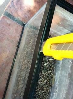 a pair of yellow handled scissors on top of a glass table with gravel and rocks