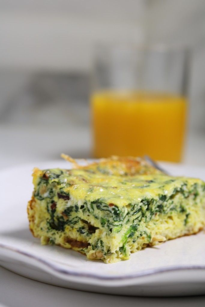 a close up of a piece of food on a plate with a glass of orange juice in the background