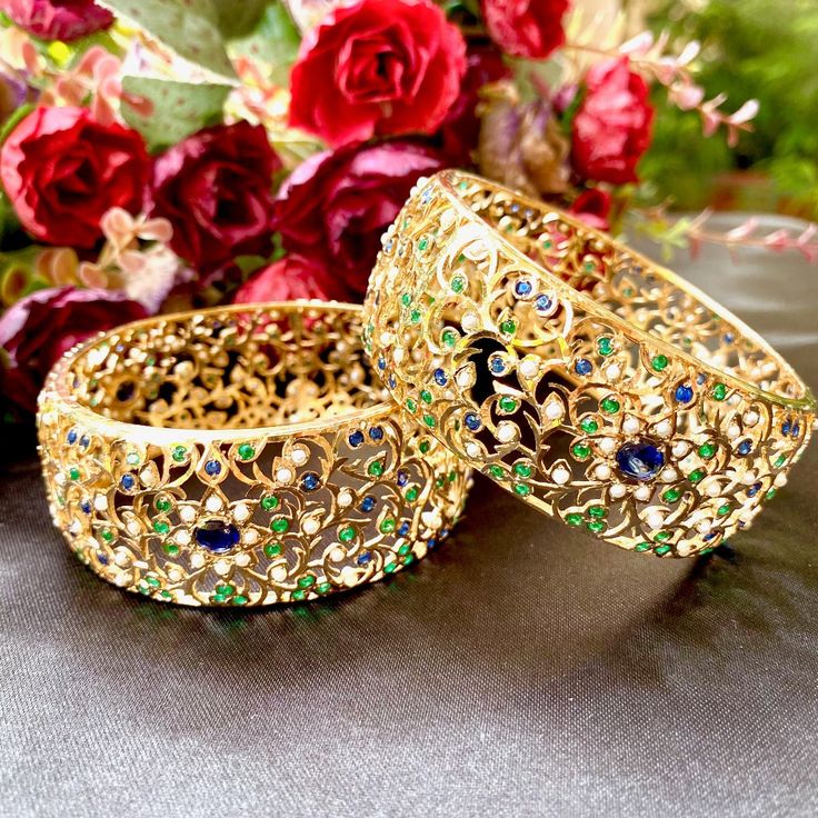 An Edwardian Era inspired pair of bangles in gold plated sterling silver. The stones in setting are precious freshwater pearls and synthetic green and blue stones that resemble blue sapphires and emeralds. The weight of the bangles is 90 GMs and the face width is 3.5 CM All our Gold Plated Jewellery is made using 925 Silver as the base metal. The beads in hanging and strings (like in our 22k gold jewelry) are always precious freshwater pearls and high quality ruby, emerald and sapphire beads. Th Elegant Multicolor Bangle With Intricate Design, Elegant Green Bangle For Festive Occasions, Elegant Multi-stone Emerald Jewelry, Fusion Style Bangle Jewelry With Gemstone Accents, Green Intricate Design Gold-plated Jewelry, Elegant Gold Bangle With Multi-stone, Elegant Gold Bangle With Multi-stone Details, Green Luxury Bangle Jewelry, Multi-stone Emerald Gold Jewelry