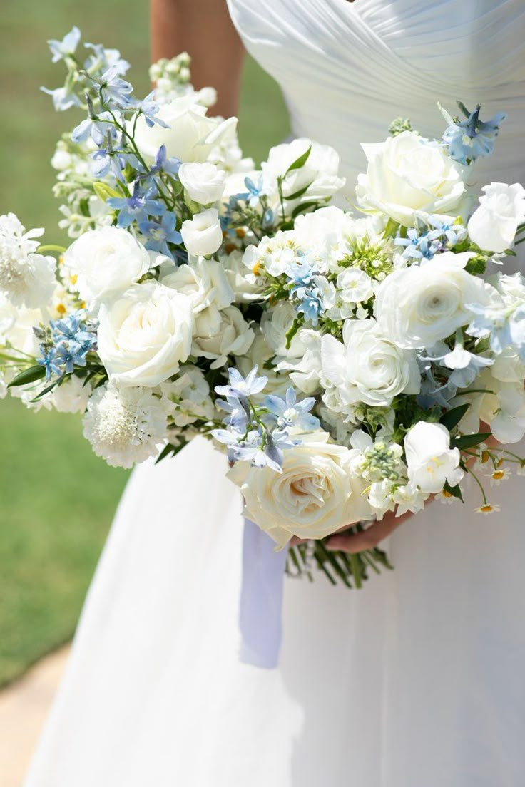 a bride holding a bouquet of white and blue flowers