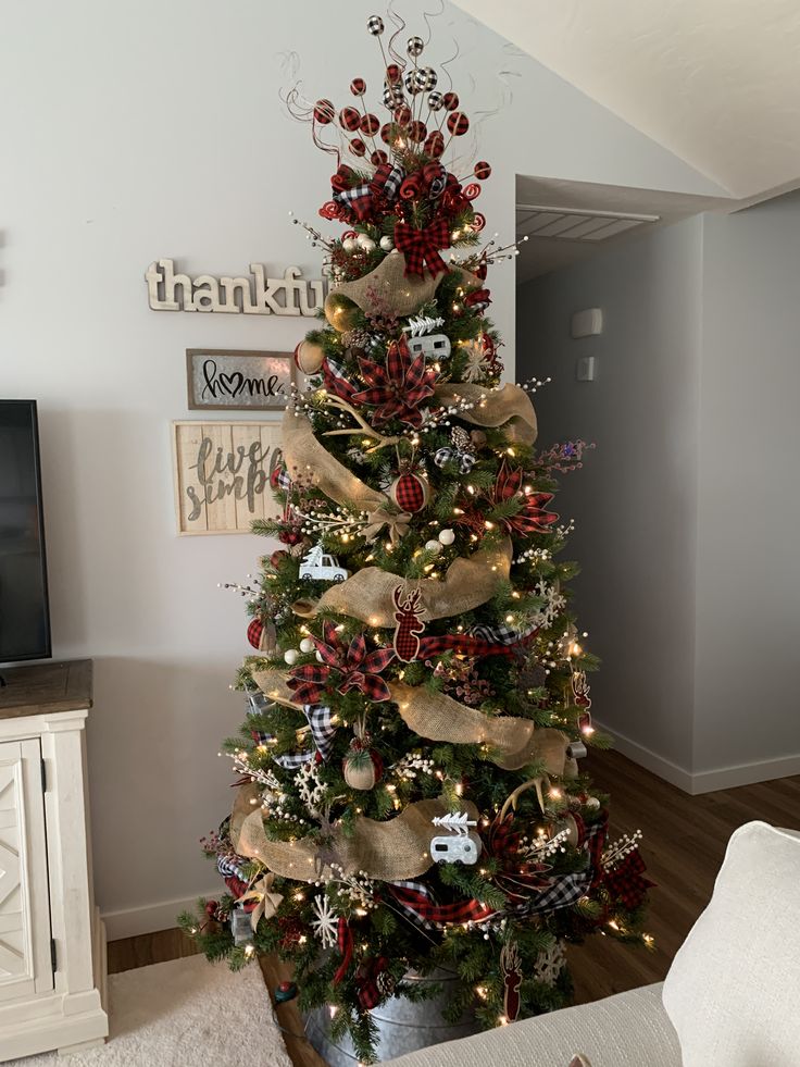 a christmas tree decorated with red, gold and silver ribbons is in the living room