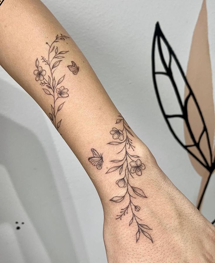 a woman's arm with flowers and leaves tattooed on the left side of her arm