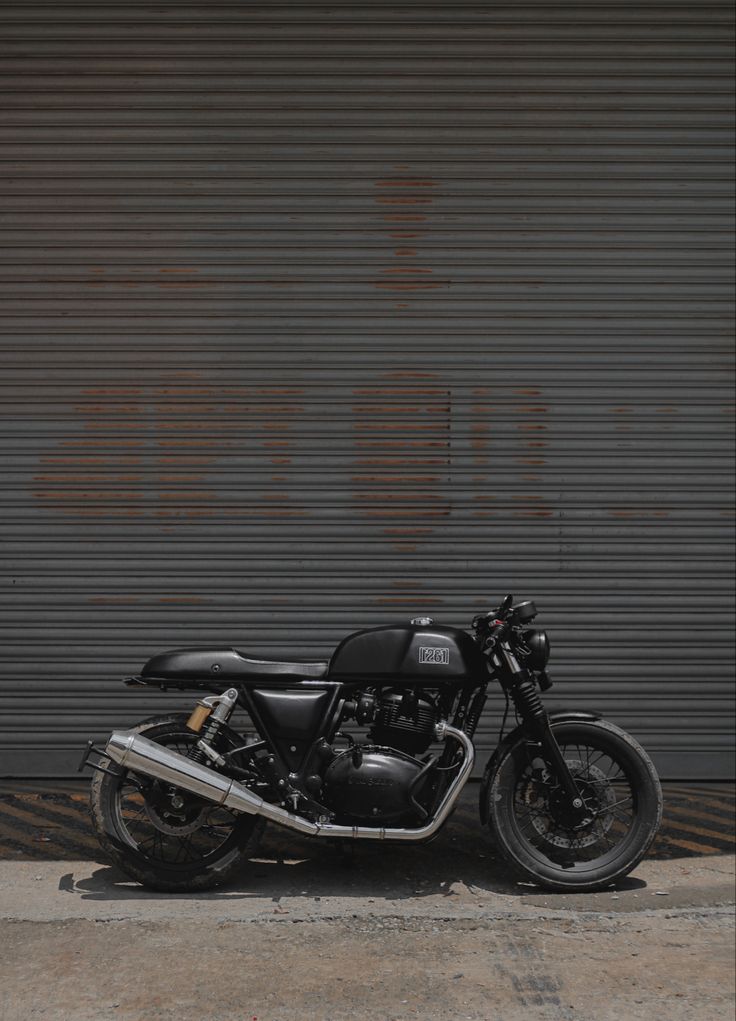 a black motorcycle parked in front of a garage door