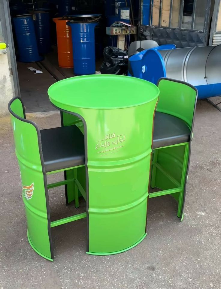 a green table and two chairs sitting next to each other in front of blue barrels