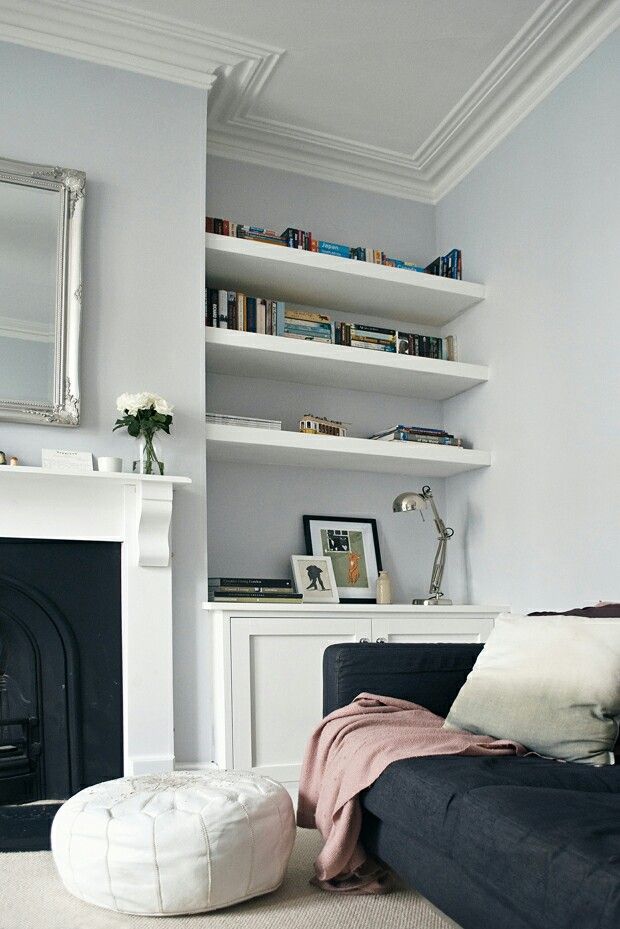 a living room filled with furniture and bookshelves next to a white fire place