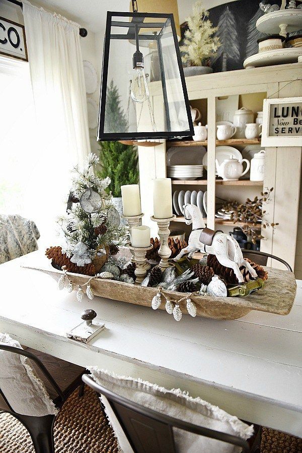 a dining room table is decorated for christmas with candles, pine cones and other holiday decorations