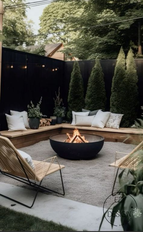 an outdoor fire pit surrounded by wooden chairs and pillows in the middle of a backyard