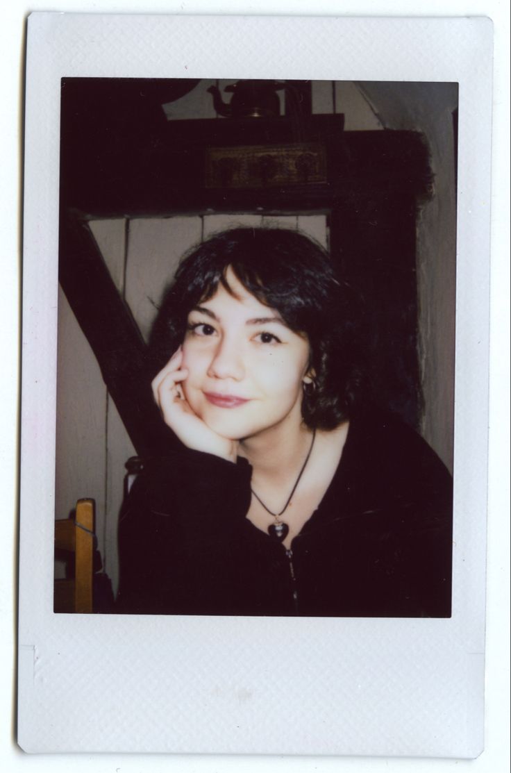 an old photo of a woman posing for the camera with her hand on her chin