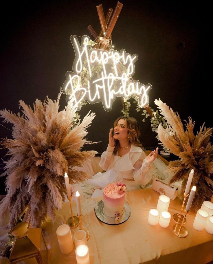 a woman sitting at a table in front of a birthday cake with candles on it