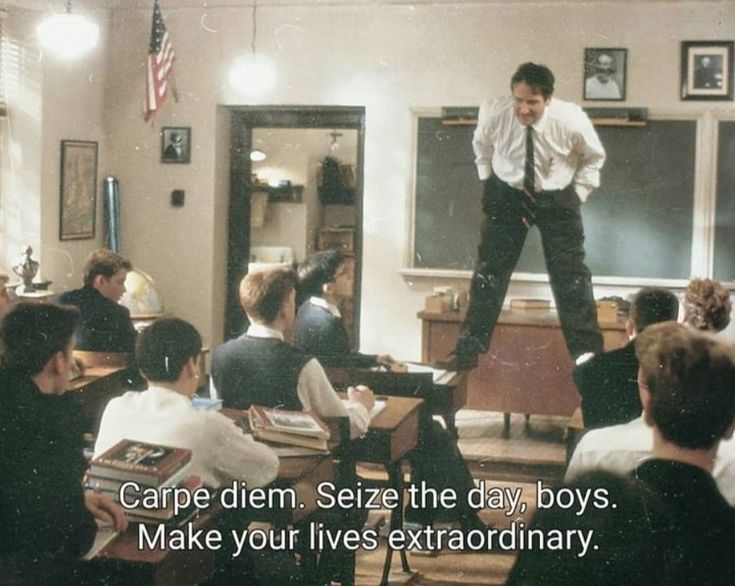 a man standing on top of a desk in a classroom