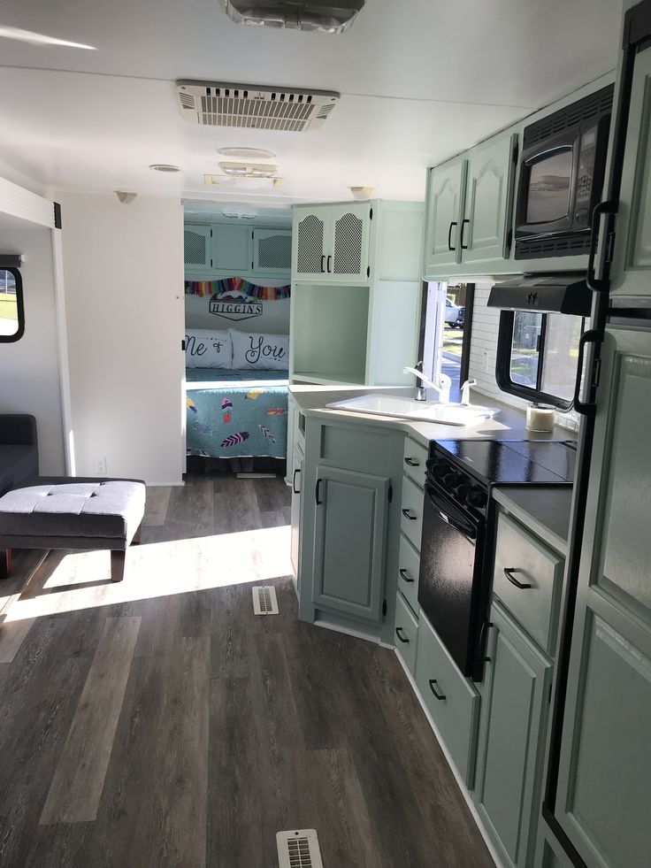 the interior of a mobile home with wood flooring and green painted cabinets, including an oven