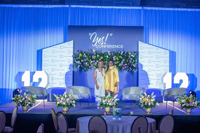 the stage is set up for an event with chairs and flowers in front of it