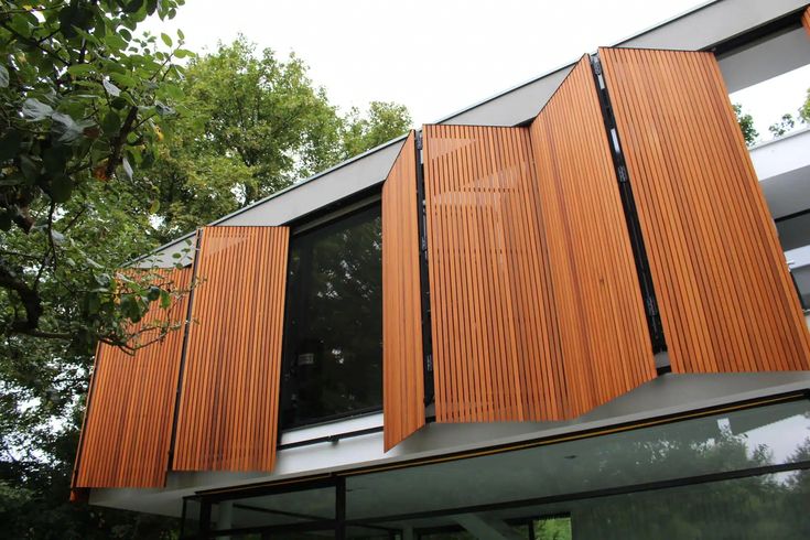 wooden slats on the side of a modern house with trees in the foreground