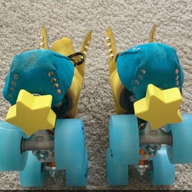 two blue roller skates with yellow wheels and spikes on the bottom one has a star