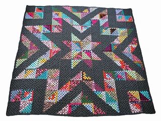 a black and multicolored quilt with stars in the center on a white background