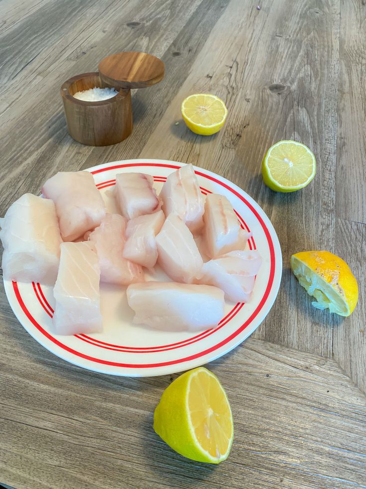 fish fillets on a plate with lemons and seasoning next to the plates