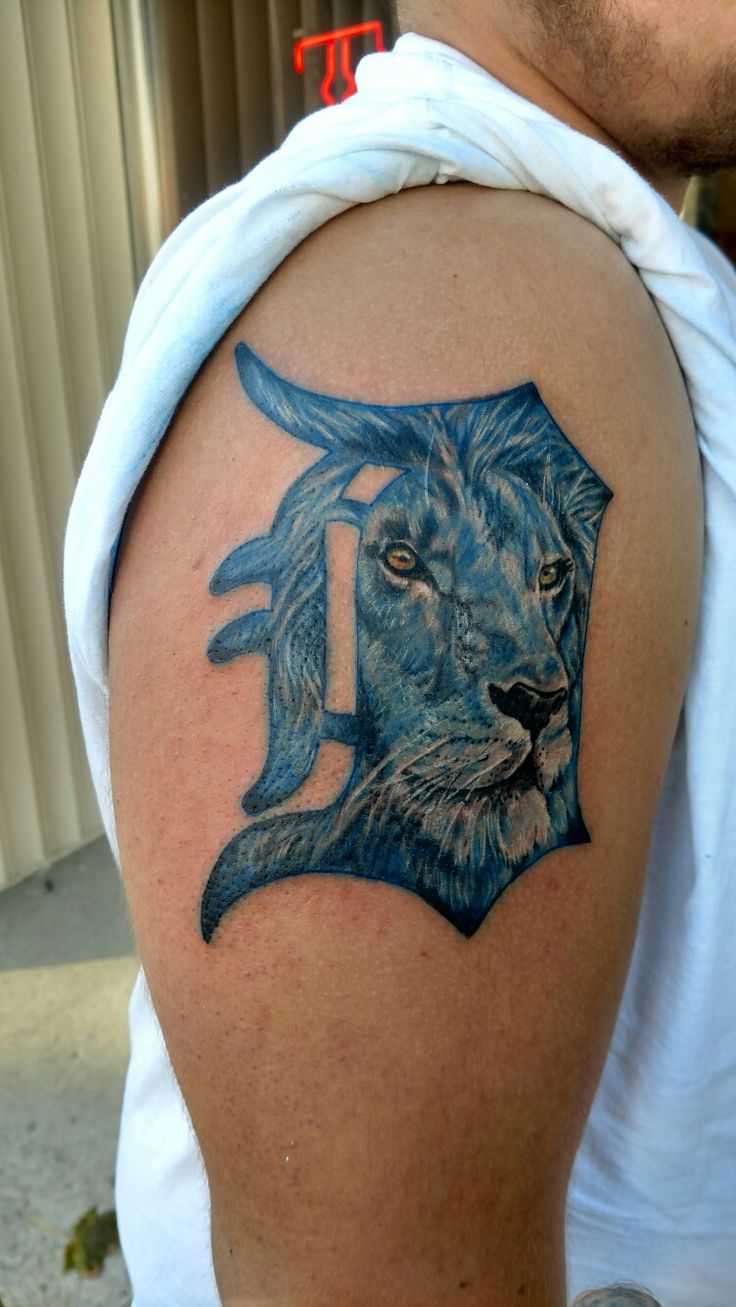 a man's arm with a lion tattoo on it and the letter j in blue ink